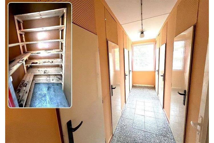 Úzká chodba s dlažbou a vestavěnými skříněmi, která nabízí přístup k několika pokojům; prostor je světlý díky velkým oknům na konci chodby.