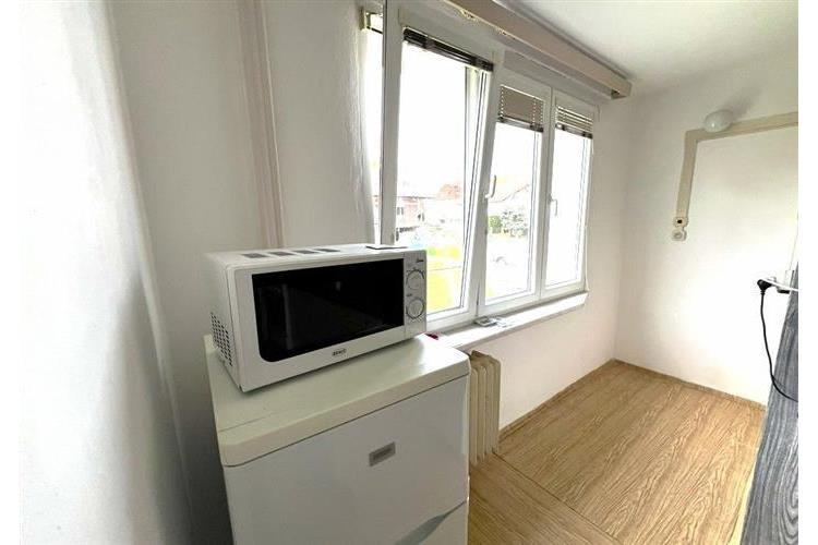 Světlá kuchyňka s parketovou podlahou nabízí velká okna pro dostatek přirozeného světla a moderní spotřebiče pro komfortní bydlení.