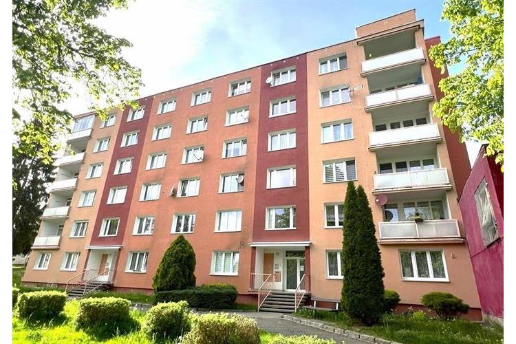 Bytový dům s moderní fasádou, velkými okny a balkóny, v klidné rezidenční čtvrti, ideální pro rodinné bydlení.