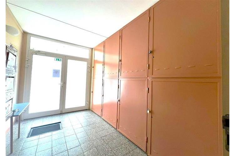 Chodba s dlažbou, vestavěné skříně a velká okna nabízí světlé prostředí. Vhodné pro moderní úložná řešení v bytovém domě.