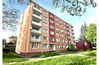Čtyřpodlažní bytový dům s balkony, obklopený trávníkem a zelení, v dobrém stavu, nachází se v klidné lokalitě.