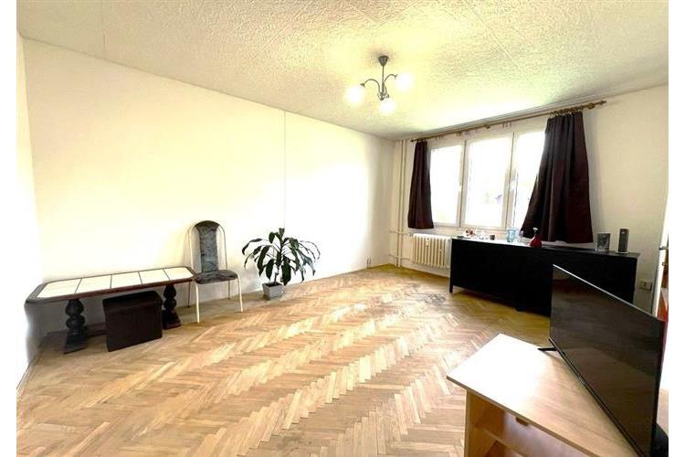 Světlý obývací pokoj s parketovou podlahou, velkými okny a světlým interiérem, ideální pro rekonstrukci a dekoraci podle vlastních představ.