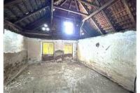 Podkrovní prostor s vysokým stropem, dřevěné trámy, nutná rekonstrukce, přirozené světlo skrz malá okna, neomítnuté cihlové zdi.