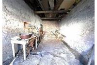 Prázdný sklepní prostor s odkrytou cihlovou stěnou, potřebující rekonstrukci, vhodný pro skladování dřeva nebo úložné účely.