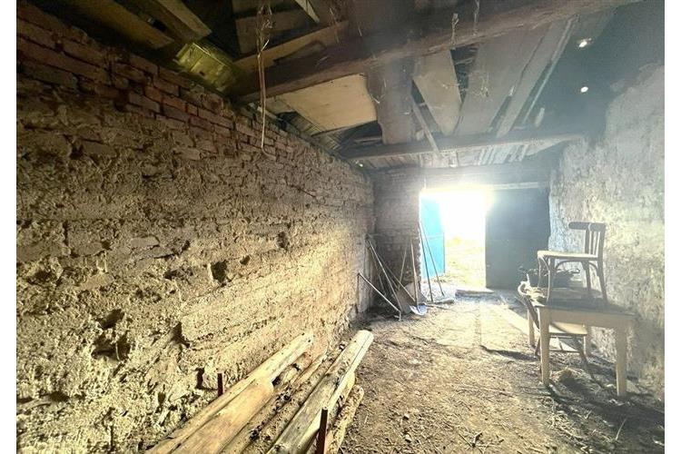 Hospodářská budova s odkrytou cihlovou zdí a půdními trámy, přírodní podlaha, vhodná pro renovaci či rekonstrukci, dobré osvětlení.