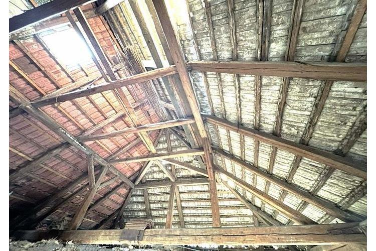 Starý podkrovní prostor s dřevěnými trámy, viditelná střešní krytina, vhodné pro rekonstrukci, možnost přeměny na obytnou místnost.