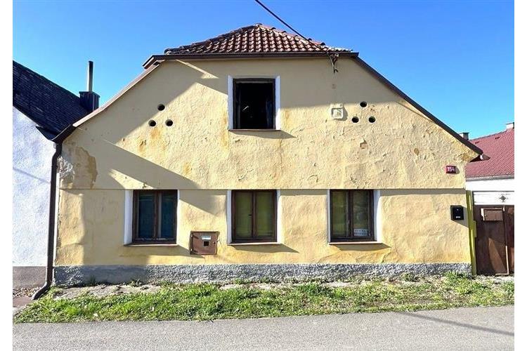 Starší rodinný dům s šikmou střechou, kamenná fasáda, dřevěná okna. Potenciál pro rekonstrukci, klidná lokalita.