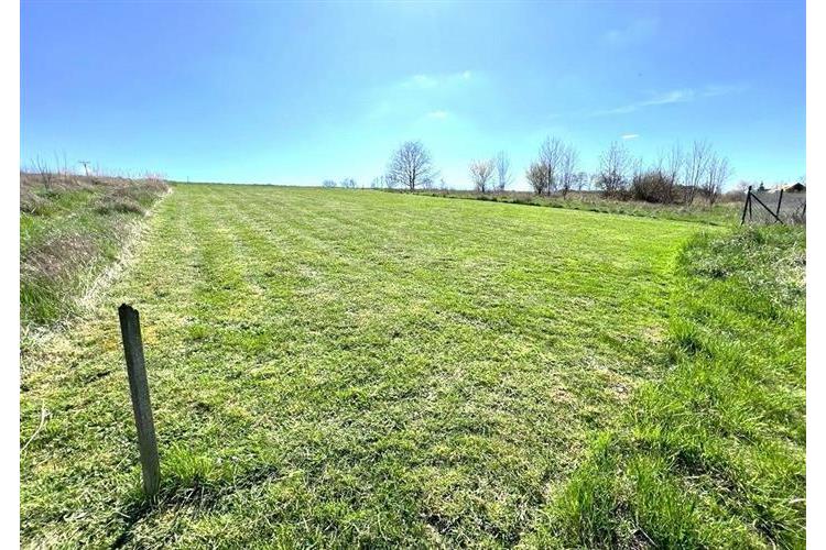 Stavební pozemek s rovinným terénem a upraveným trávníkem, ideální pro výstavbu. Klidná lokalita obklopená zelení, skvělá investiční příležitost.