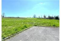 Travnatý pozemek s asfaltovou příjezdovou cestou, ideální pro stavbu, slunná lokalita, rovný terén, vhodné pro rodinný dům.