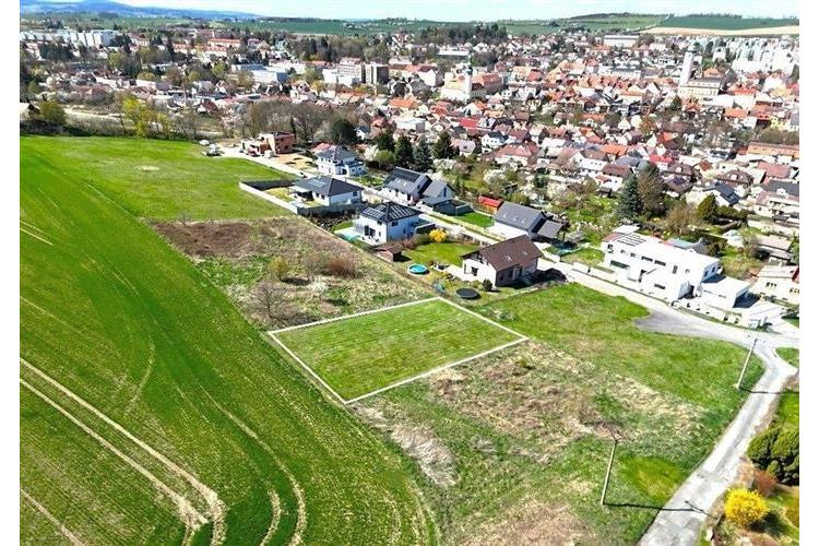 Stavební pozemek na okraji města, rovný terén, klidná lokalita s výhledem na okolní přírodu a blízká dostupnost do centra, ideální pro rodinný dům.