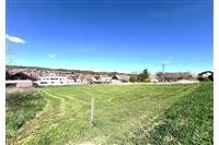 Zahrada s udržovaným trávníkem, obklopená výhledem na okolní domy, ideální k rekreaci nebo stavbě, klidná lokalita s potenciálem rozvoje.