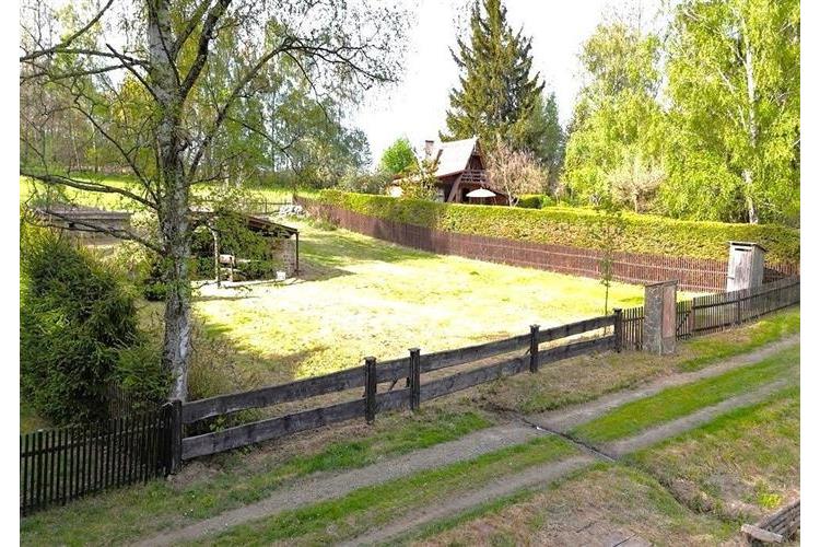 Rozlehlá zahrada s dřevěným altánem, obklopená přírodní květenou a vzrostlými stromy, nabízí klidné prostředí pro relaxaci a rekreaci.
