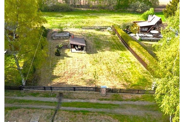 Zahrada s trávníkem a dřevěným altánem, obklopená plotem. Vhodné pro klidné bydlení, rekreaci nebo zahradničení.